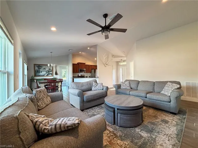 Living room with vaulted ceiling, a ceiling fan, visible vents, recessed lighting, and wood-style tile  flooring