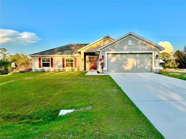 Single story home featuring driveway, a garage, a front lawn, and stucco siding