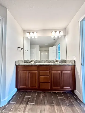 Master Bathroom with double vanity, a sink, and wood finish floors