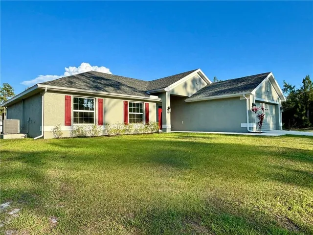 Ranch-style home with stucco siding, a garage, central AC, and a front yard