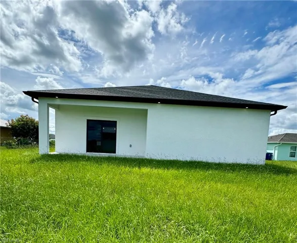 Back of house featuring stucco siding and a lawn