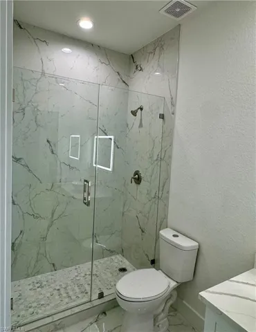 Full bathroom featuring marble finish flooring, a marble finish shower, vanity, a textured wall, and recessed lighting