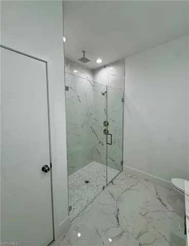 Full bath featuring a marble finish shower, light marble finish flooring, and recessed lighting