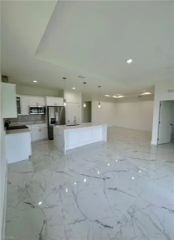 Unfurnished living room with light marble finish floors and recessed lighting