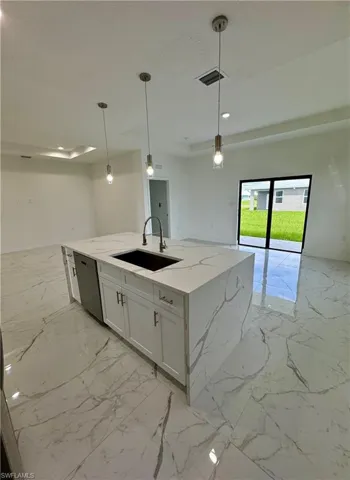 Kitchen with light marble finish flooring, open floor plan, light stone counters, pendant lighting, and recessed lighting
