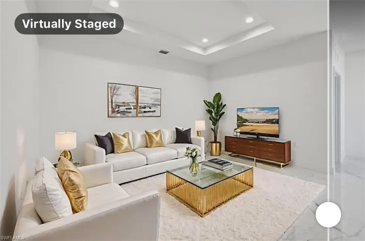 Living area with recessed lighting, a raised ceiling, and light marble finish floors