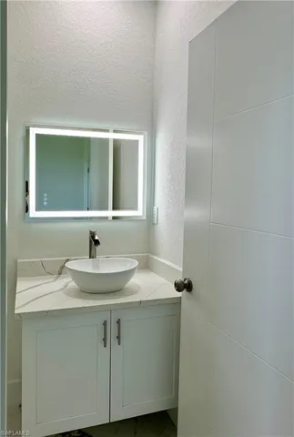 Bathroom with a textured wall and vanity