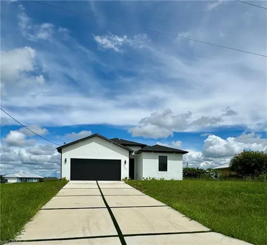 View of front of home with stucco siding, driveway, and an attached garage