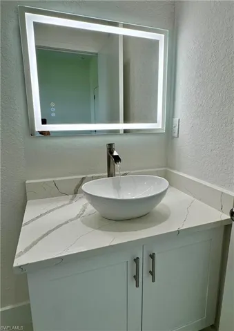 Bathroom featuring a textured wall and vanity