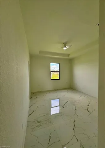 Spare room with light marble finish flooring, a raised ceiling, and a textured wall