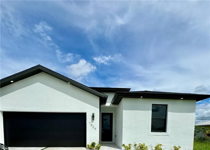 View of front of home featuring stucco siding, a garage, and driveway