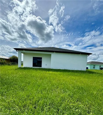 Back of house with stucco siding and a lawn