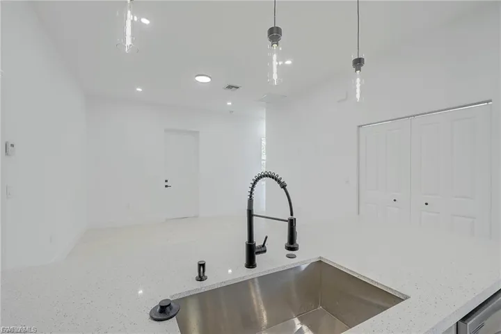 Kitchen view of light stone countertops and pendant lighting