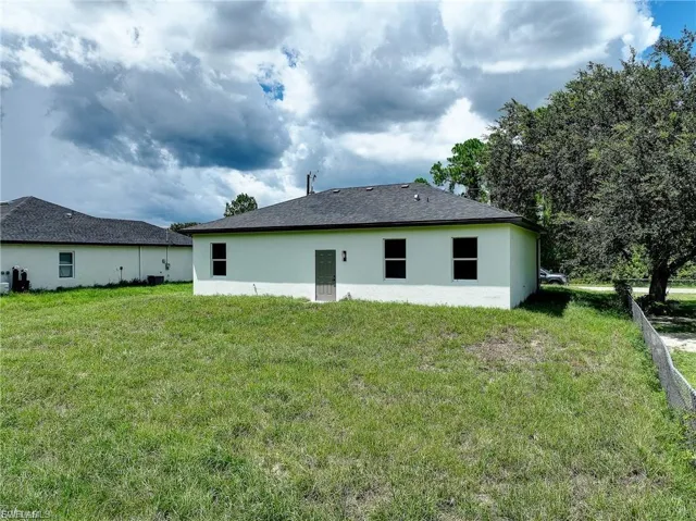 Rear view of house featuring stucco siding and a yard