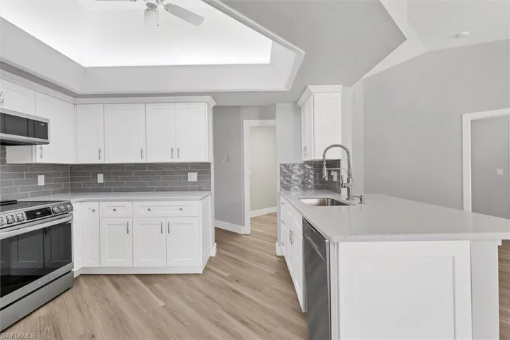 Kitchen featuring stainless steel appliances, light stone counters, decorative backsplash, and light wood-type flooring