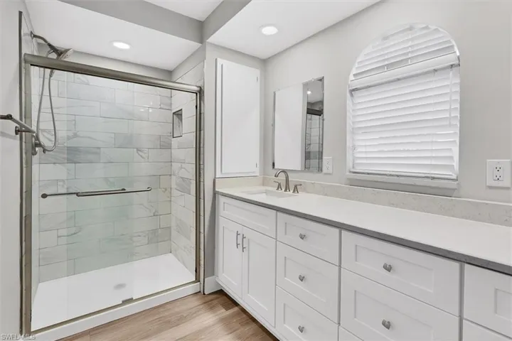 Bathroom with vanity, a shower stall, and light wood-style floors