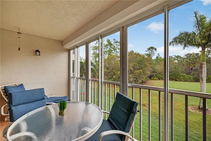 Sunroom with a textured wall, a balcony, outdoor dining space, and a textured ceiling
