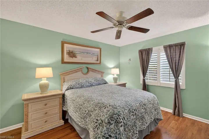 Bedroom with dark wood-style flooring, a ceiling fan, and a textured ceiling
