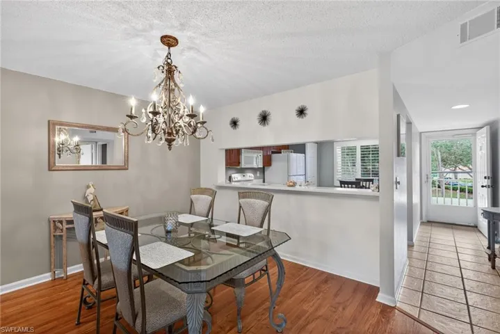 Dining space with light wood-style flooring, a textured ceiling, and a chandelier