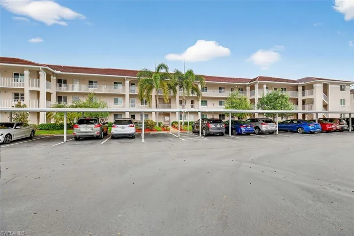 View of apartment building / complex featuring covered parking