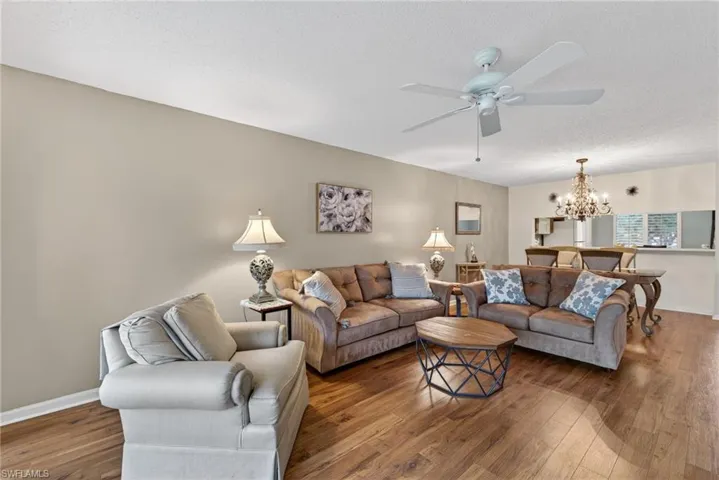 Living area featuring a chandelier, hardwood / wood-style flooring, a ceiling fan, and a textured ceiling