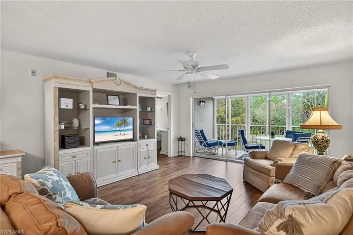 Living room with hardwood / wood-style flooring, a ceiling fan, and a textured ceiling
