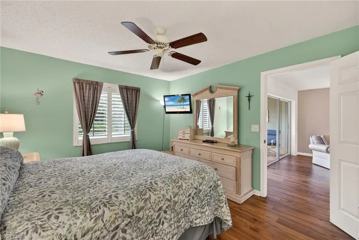 Bedroom featuring dark wood-style floors, a textured ceiling, and ceiling fan