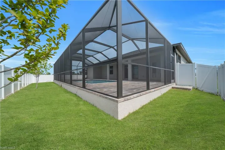 Back of house with a fenced backyard, a sunroom, a gate, and a lanai