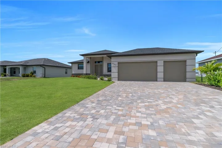 Prairie-style home featuring a garage, decorative driveway, a front yard, and stucco siding