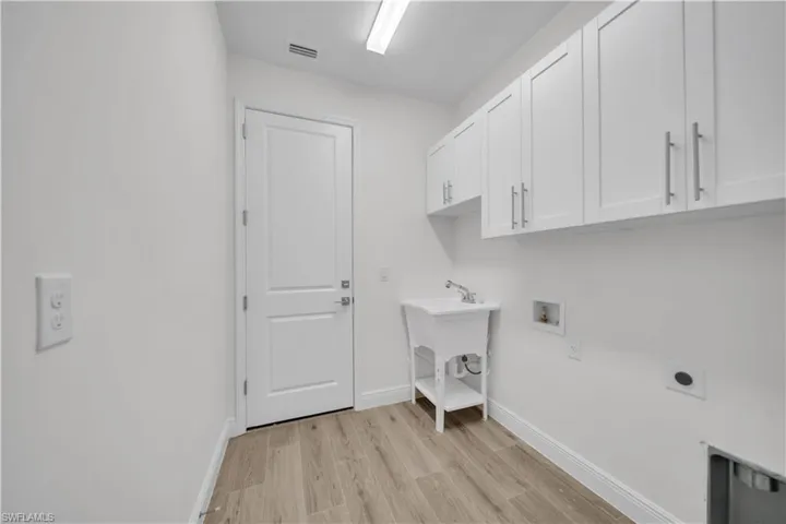 Laundry area with light wood finished floors, hookup for an electric dryer, washer hookup, and cabinet space
