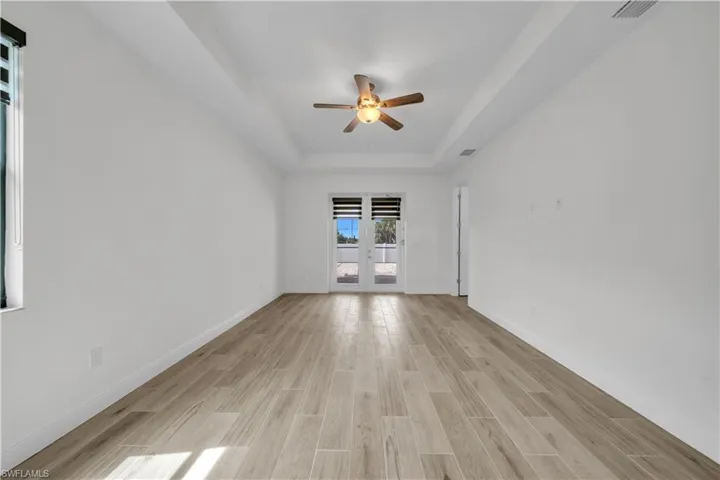 Spare room featuring wood tiled floors, french doors, a ceiling fan, and a tray ceiling