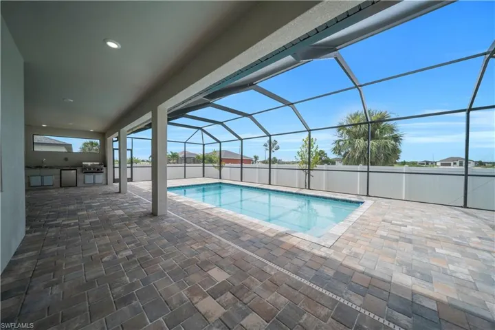 View of pool featuring area for grilling, glass enclosure, patio surround, a sunroom, and a fenced backyard