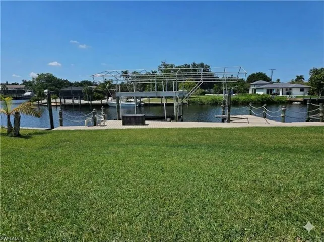 Dock with boat lift, a yard, and a water view