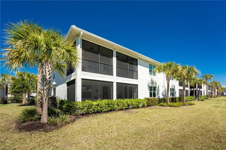 Back of property featuring a sunroom, a balcony, a yard, and stucco siding
