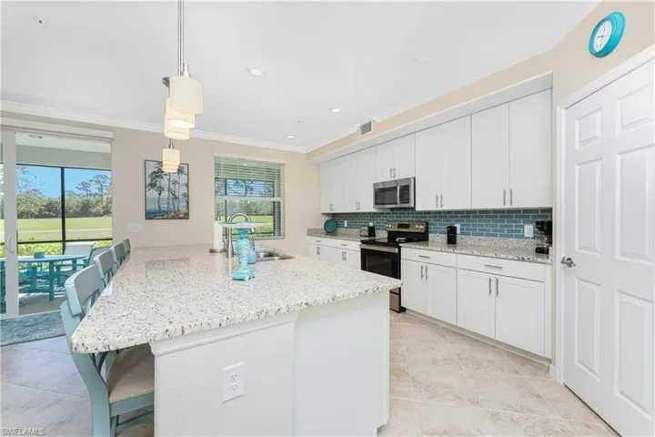 Kitchen featuring a kitchen breakfast bar, decorative backsplash, stainless steel appliances, pendant lighting, and white cabinetry