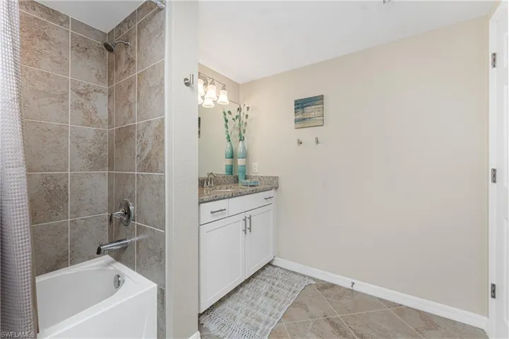 Full bath featuring shower / bath combination with curtain, vanity, and light tile patterned floors