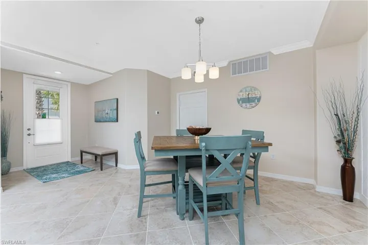 Dining area featuring light tile patterned flooring, a chandelier, and ornamental molding