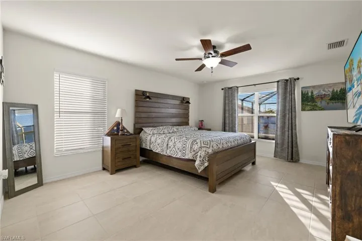 Primary Bedroom with ceiling fan, En Suite Bath, & view of pool
