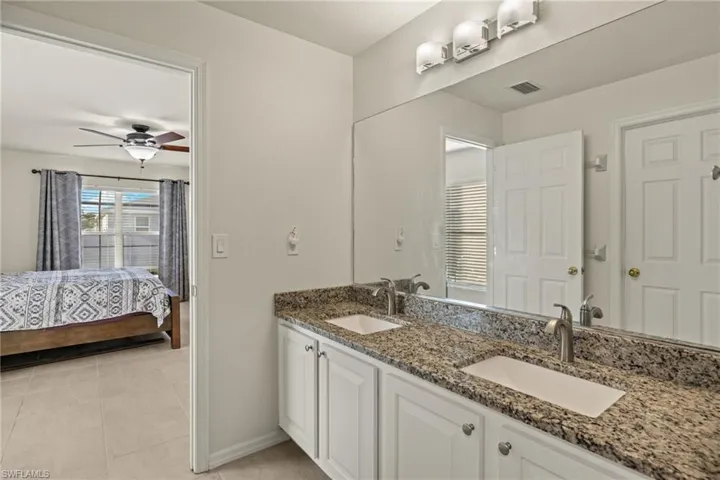 En Suite Bath with granite counter top dual vanity, walk-in shower, walk-in closet, and extra closet