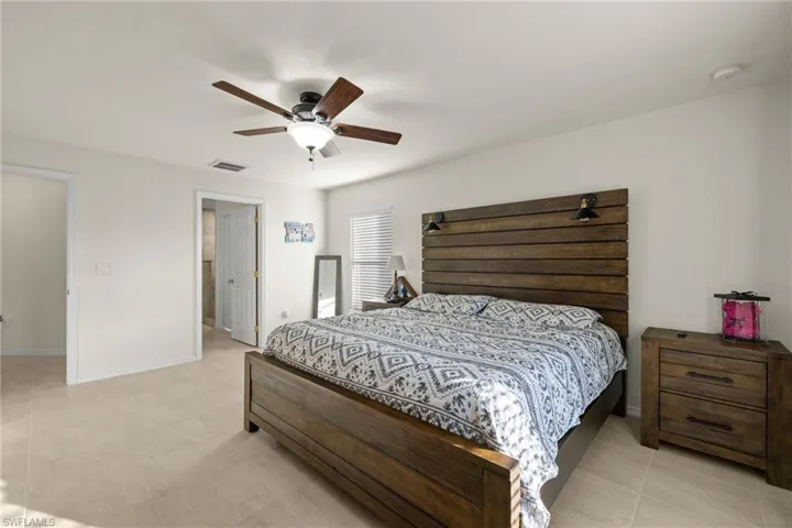 Primary Bedroom with ceiling fan, En Suite Bath, & view of pool
