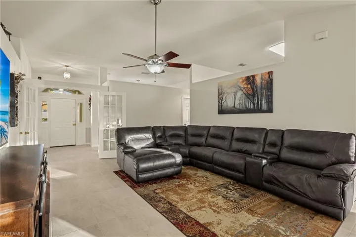 Living room featuring French Doors with tile flooring, ceiling fan, Cathedral Ceiling