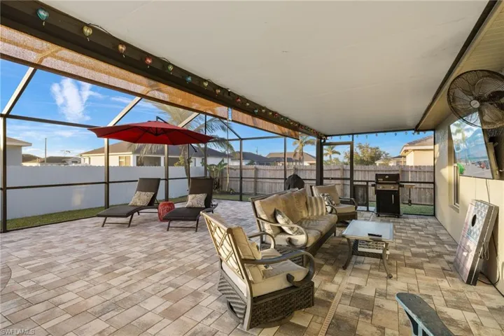 Large, screened pool enclosure with outdoor living space, roll down shades, & pavered tiles