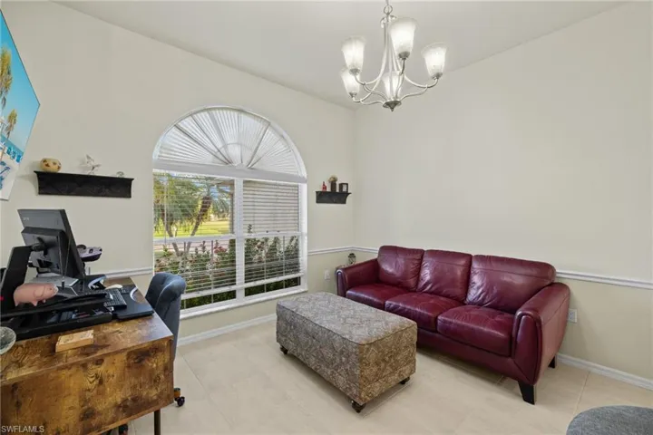 Den features chandelier and arched window