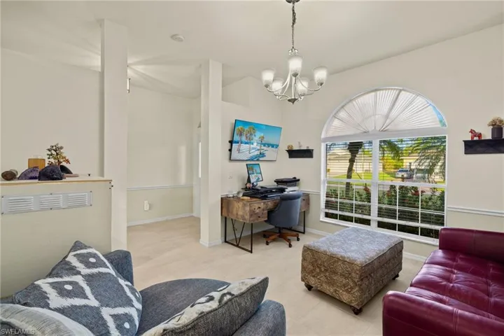 Den features chandelier and arched window