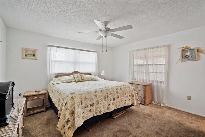 Carpeted bedroom with ceiling fan and a textured ceiling