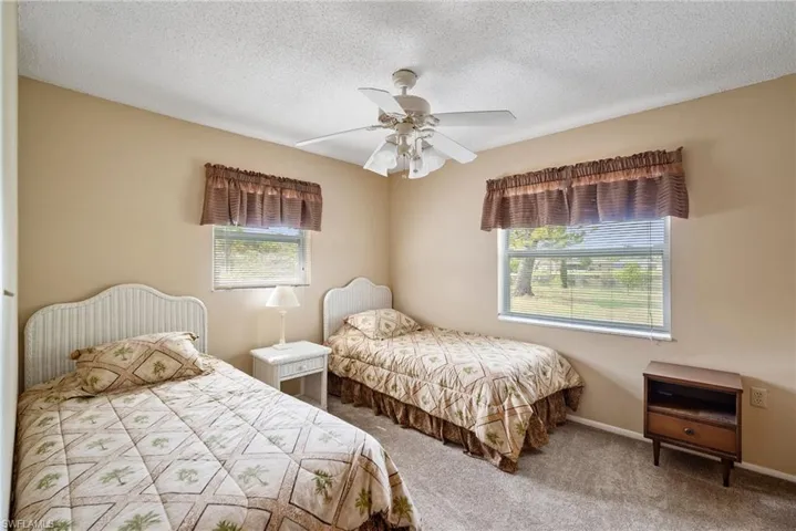 Bedroom featuring a textured ceiling, carpet, multiple windows, and ceiling fan