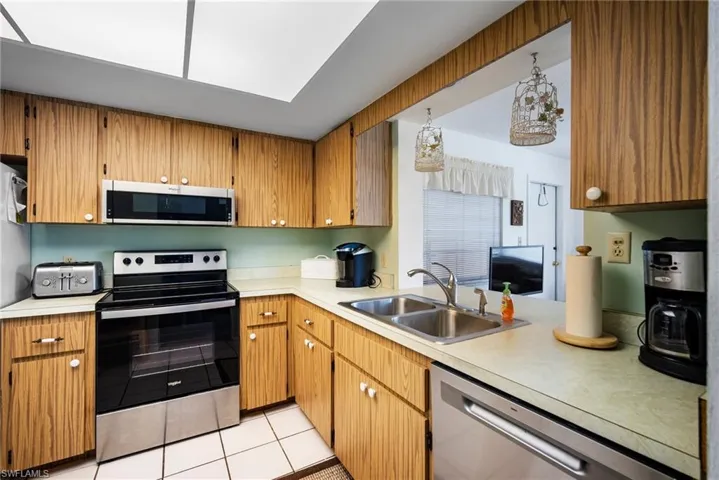 Kitchen with appliances with stainless steel finishes, sink, and light tile floors