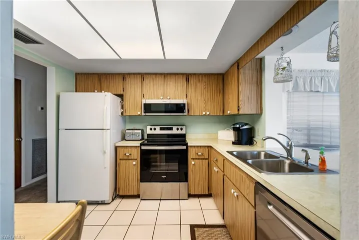 Kitchen with sink, light tile flooring, and appliances with stainless steel finishes