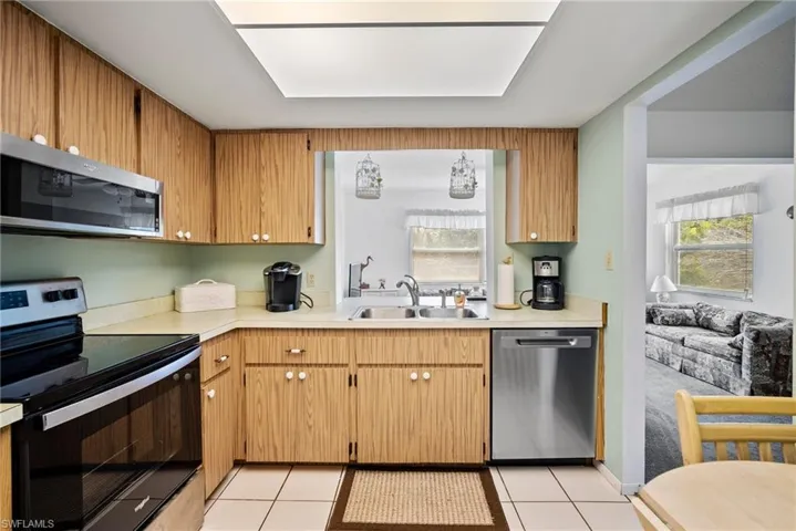 Kitchen with stainless steel appliances, sink, and light tile floors