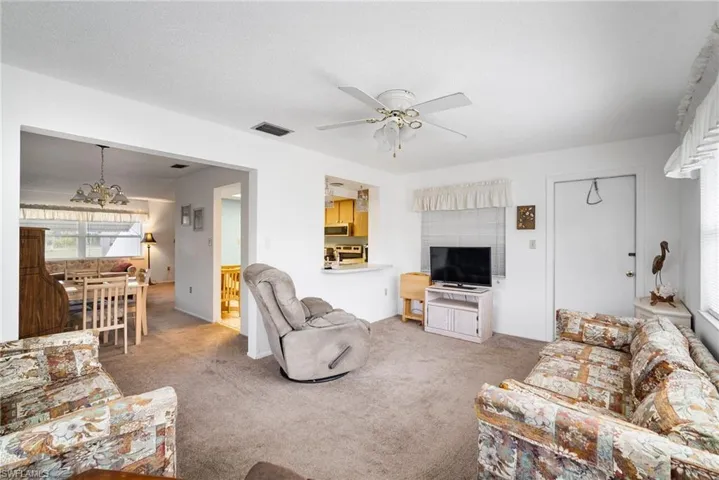 Carpeted living room featuring ceiling fan with notable chandelier